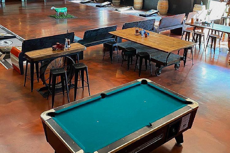 Interior image of pool table next to empty tables.